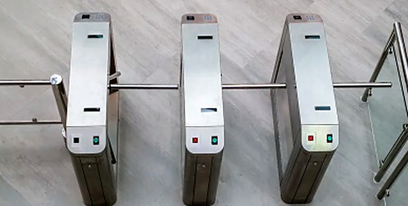 Três torniquetes tripé com leitor de cartão, vistos de cima, num átrio de entrada