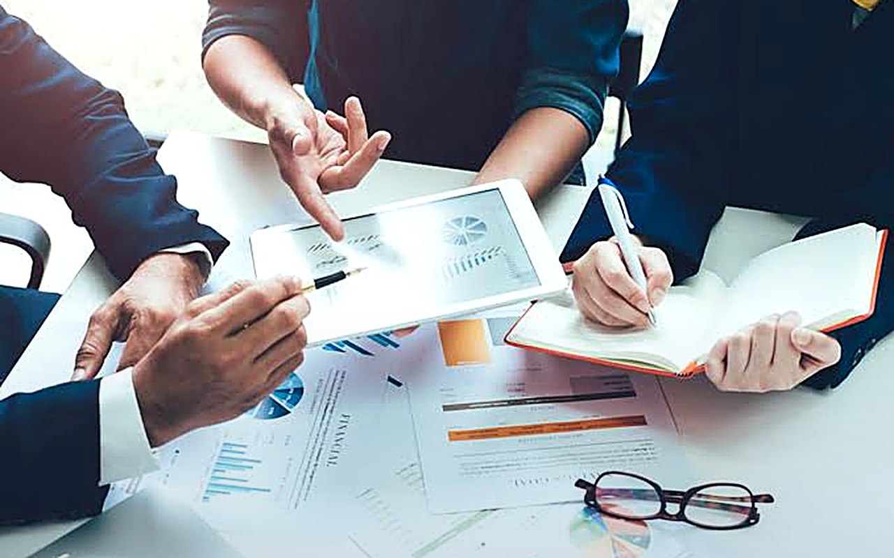 Equipa em reunião de trabalho a analisar gráficos e relatórios numa mesa