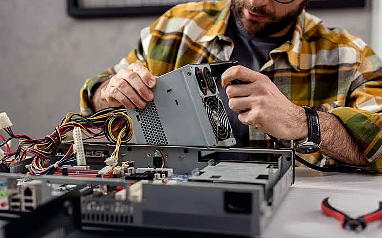 Técnico a reparar a fonte de alimentação de um computador de secretária aberto